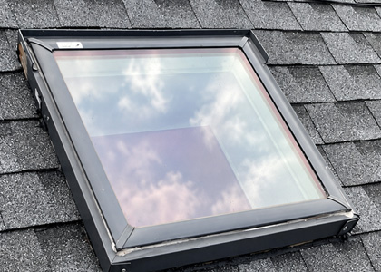 Residential skylight with repaired flashing and surrounding asphalt shingles