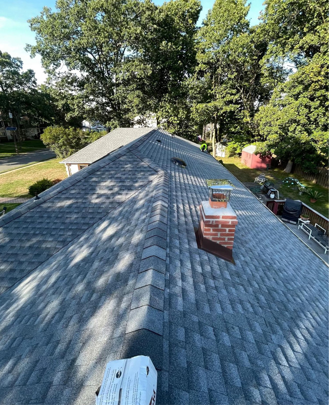 Completed residential asphalt shingle roofing project with chimney in Passaic County NJ